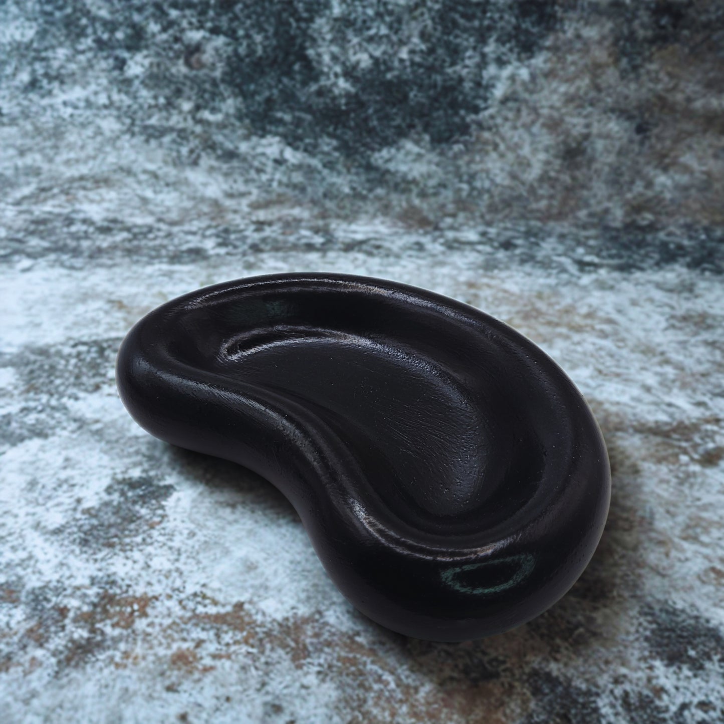 Black jellybean key bowl on a textured stone surface