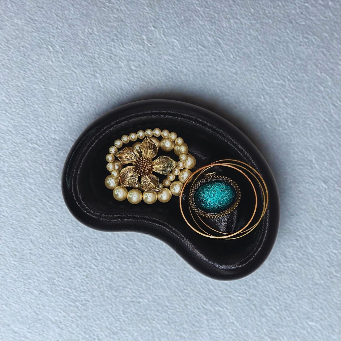 Three vintage brooches on a black stone with a light blue background