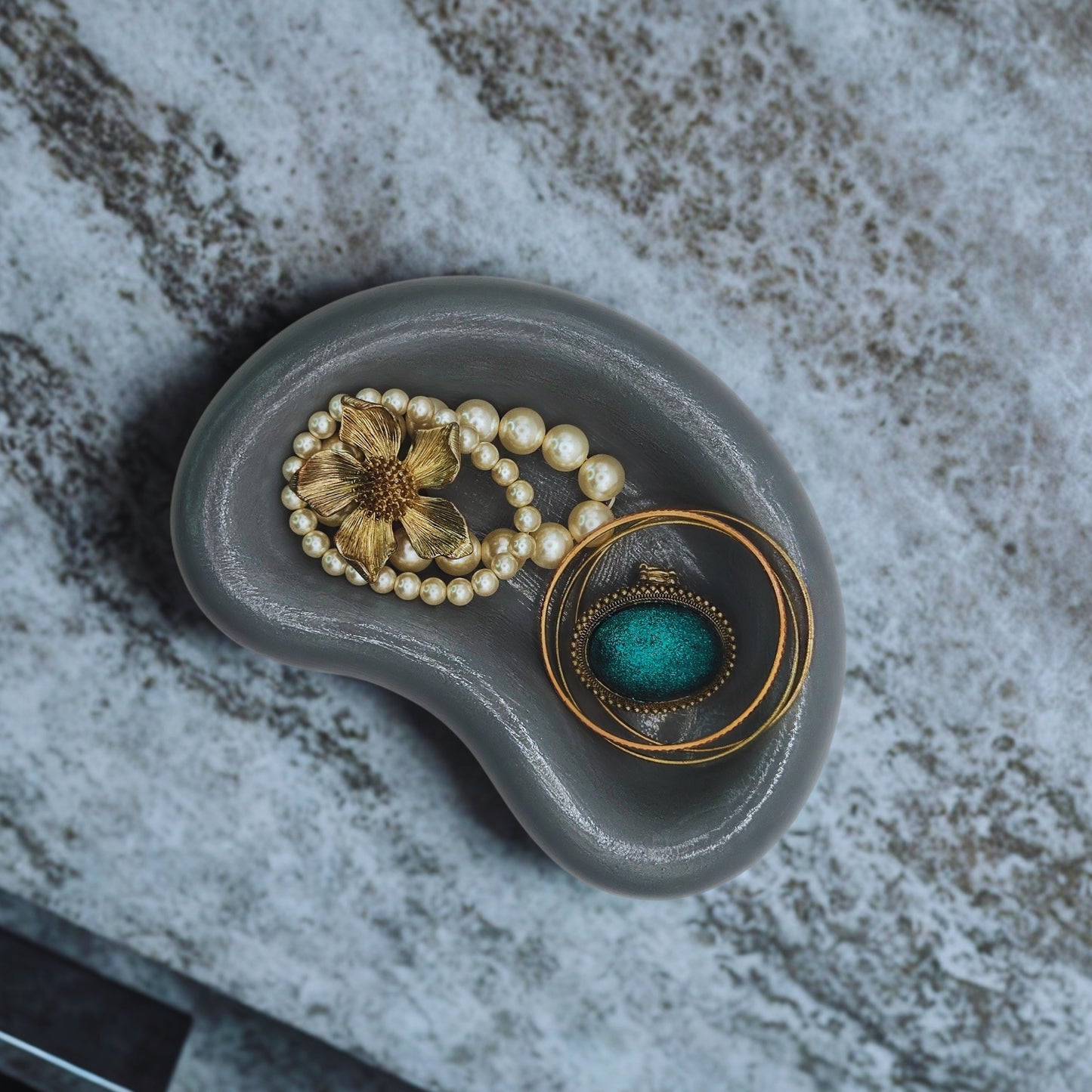 jellybean key bowl with a pearl bracelet and decorative box on a textured surface