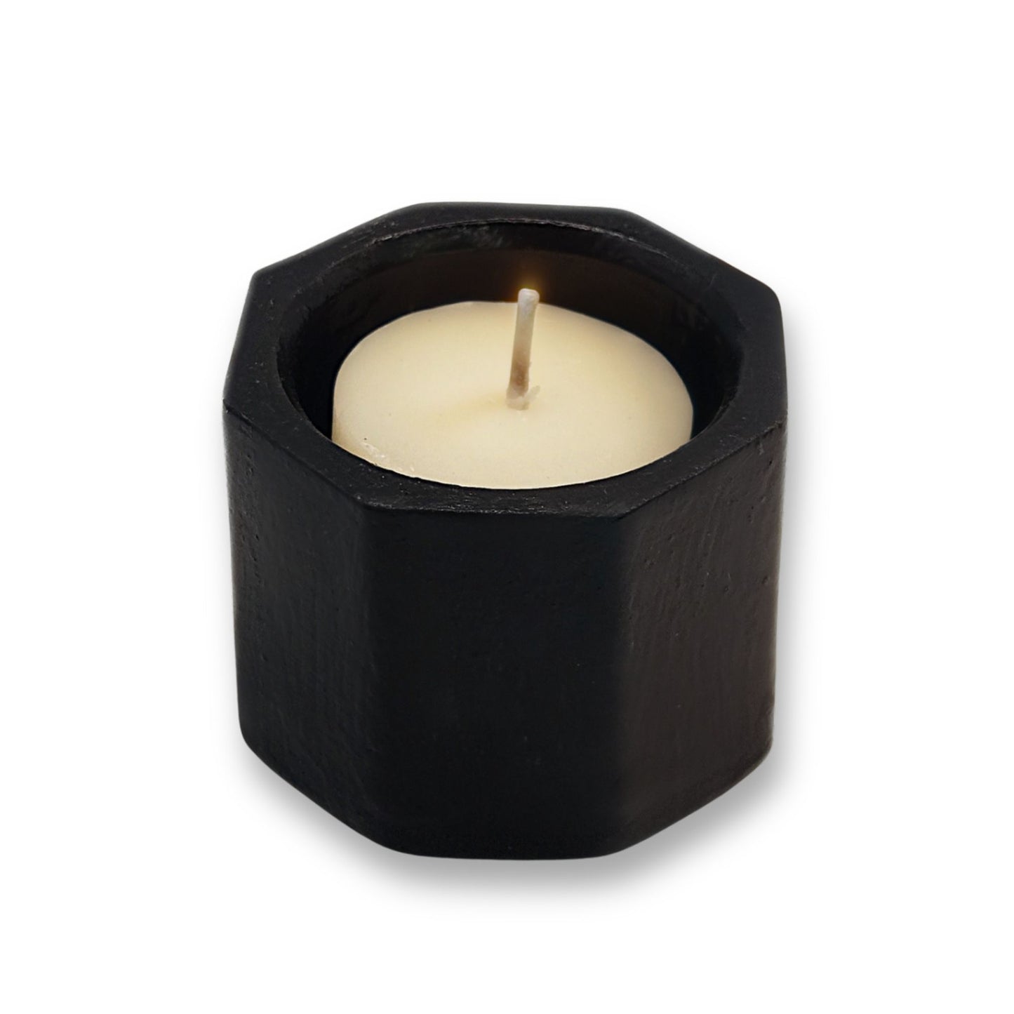 Hexagonal black candle holder with a white candle on a white background