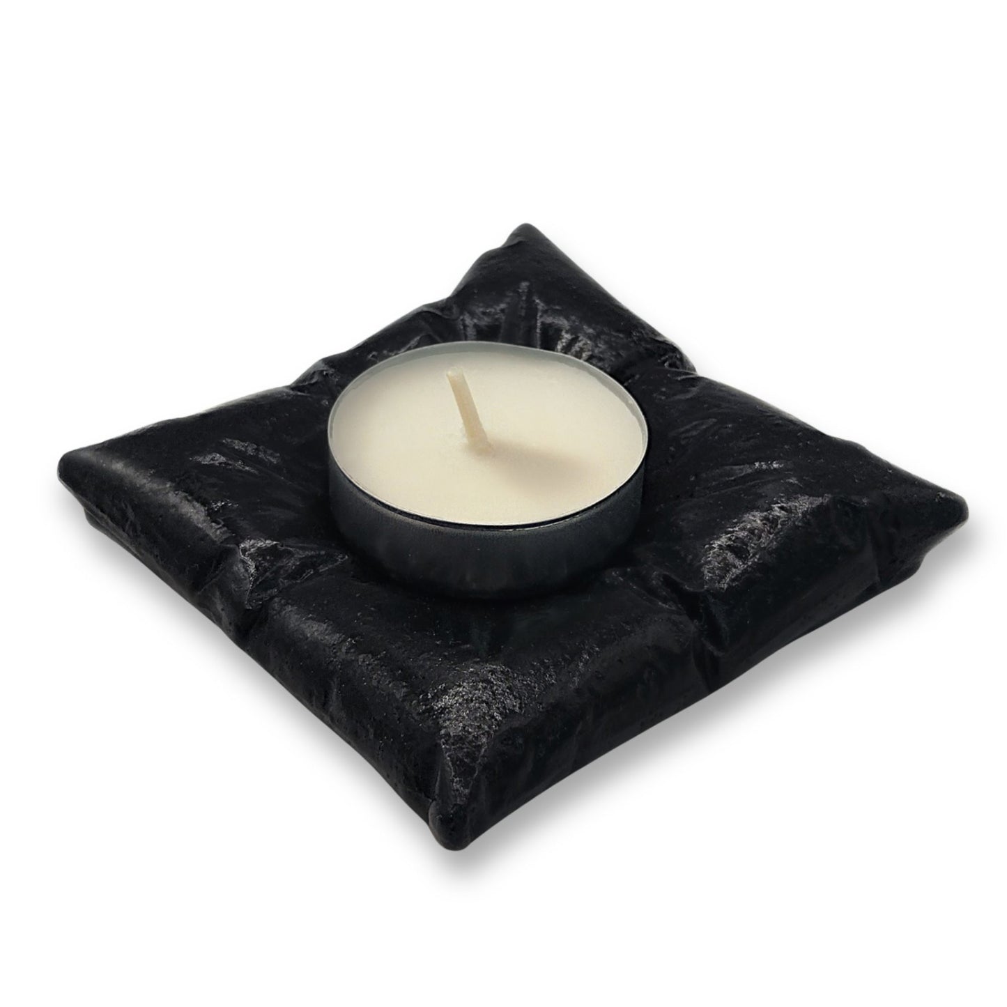 Black candle holder with a white candle on a white background