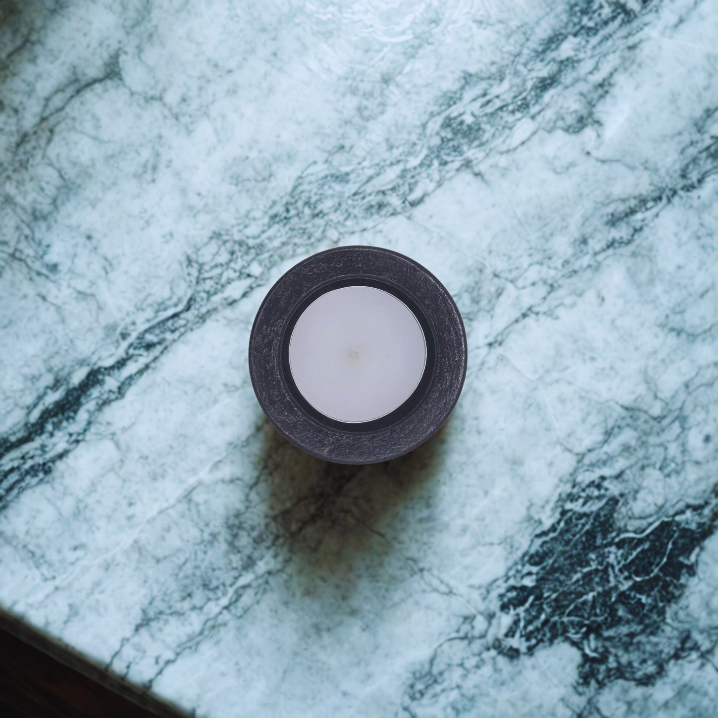 Tealight candle in a black holder on a marble surface