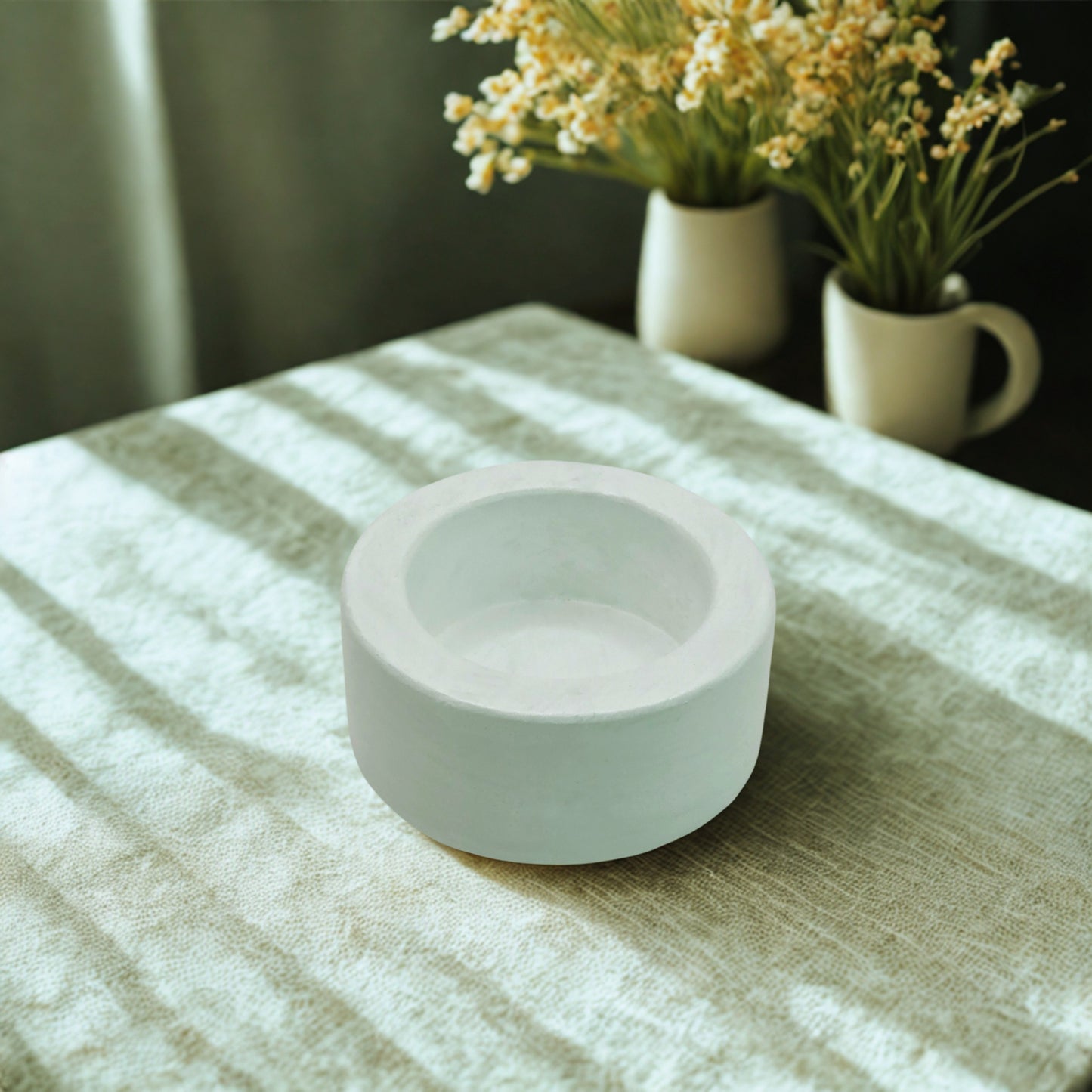 White round tealight holder on a textured surface with blurred background