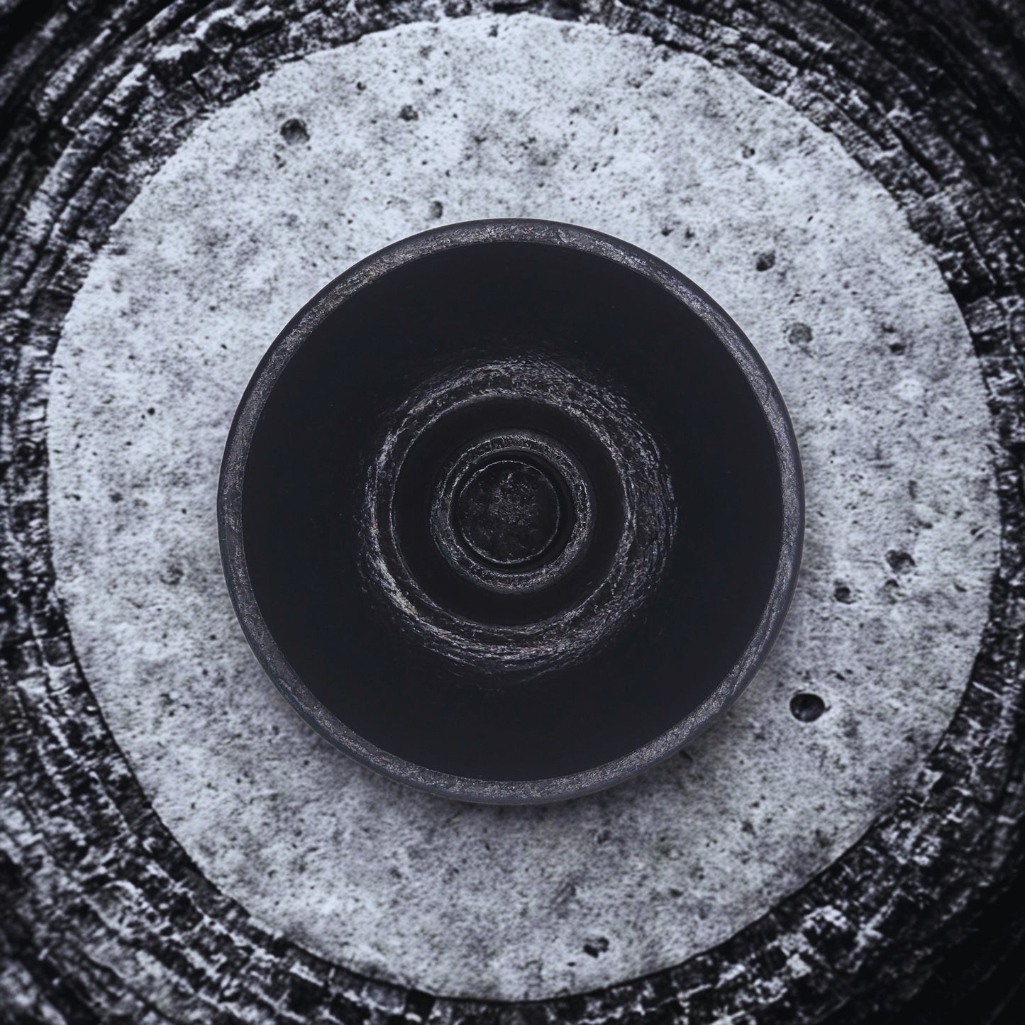 Close-up of a round candlestick holder with concentric circular patterns on a textured surface