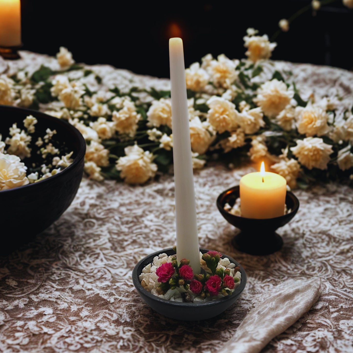 Candle in a decorative holder with flowers on a lace tablecloth