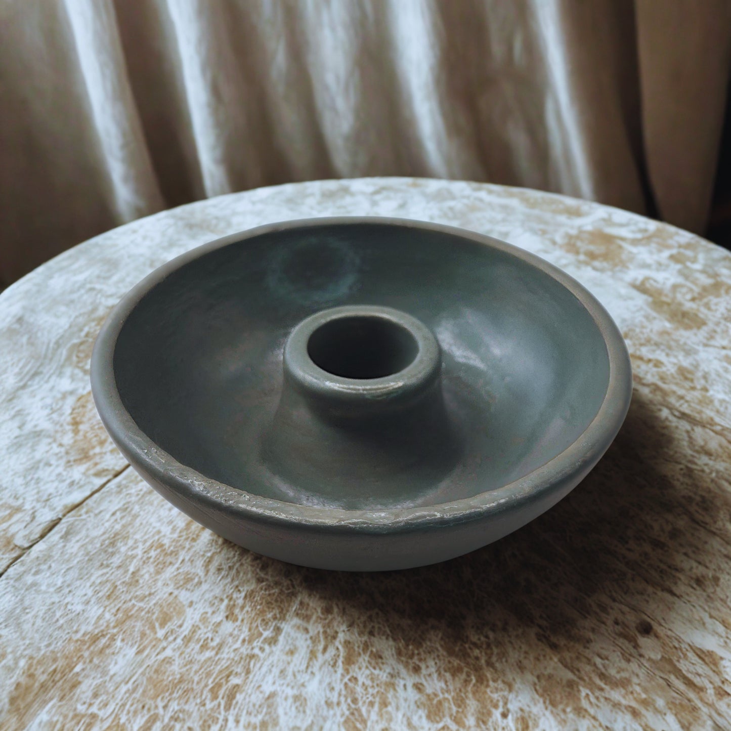 round candlestick holder on a marble surface with a neutral background