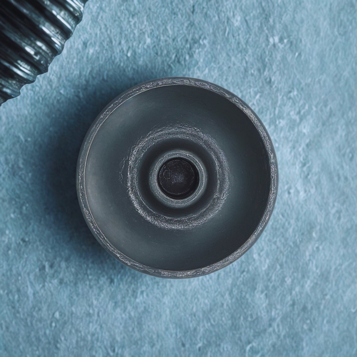 Close-up of a round candlestick holder on a textured blue background