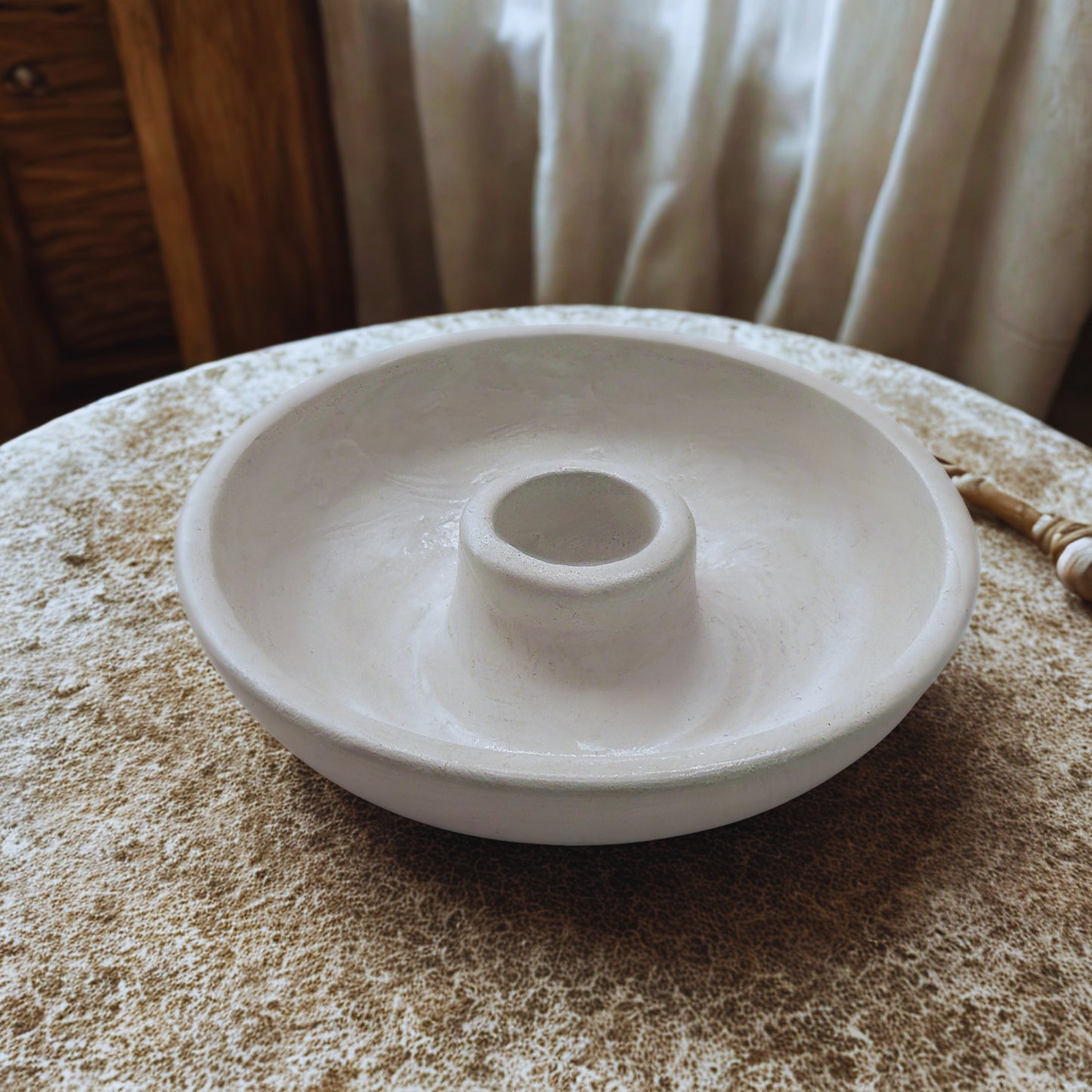 White round candlestick holder on a textured surface with a blurred background