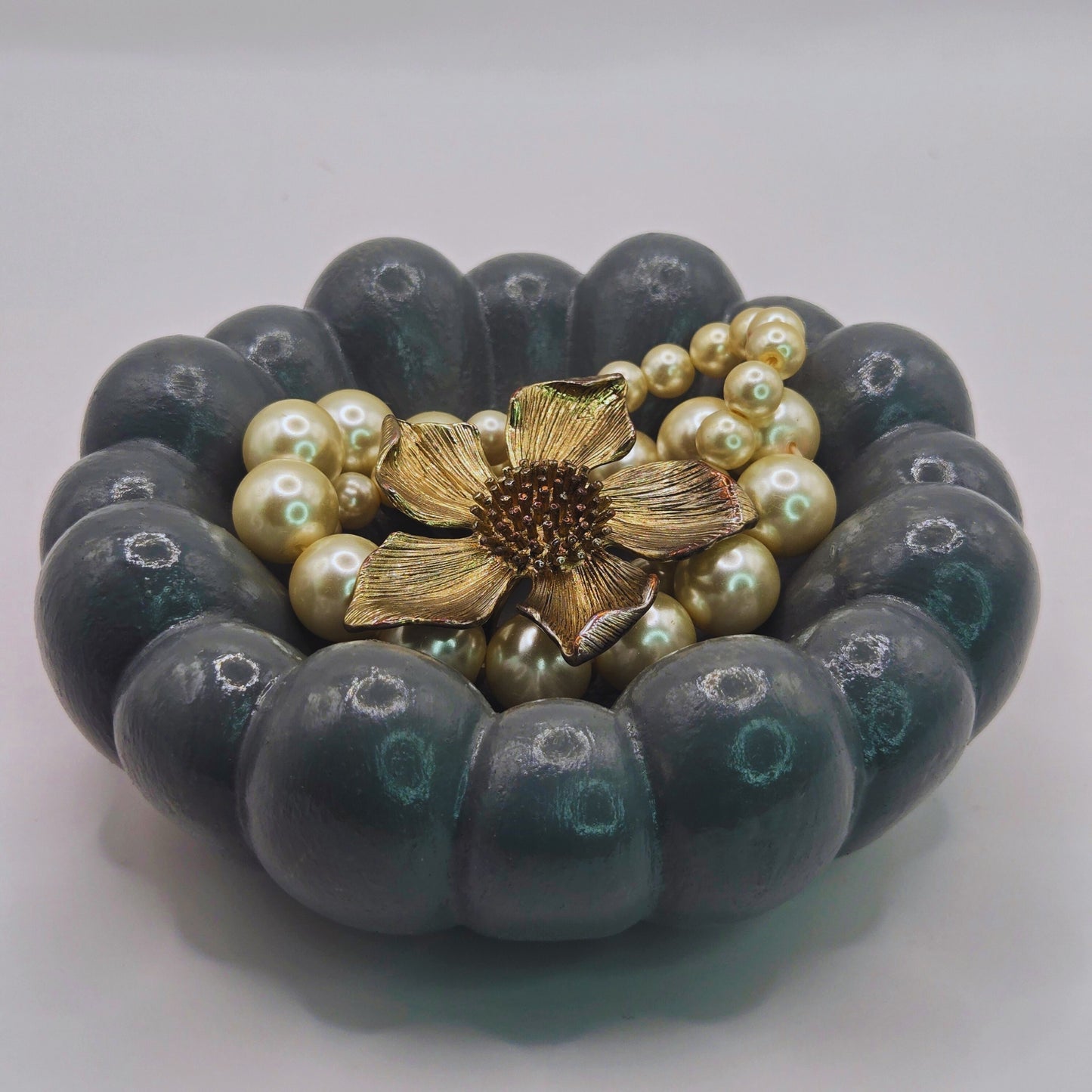 Bracelet with green beads and gold flower clasp on a white background