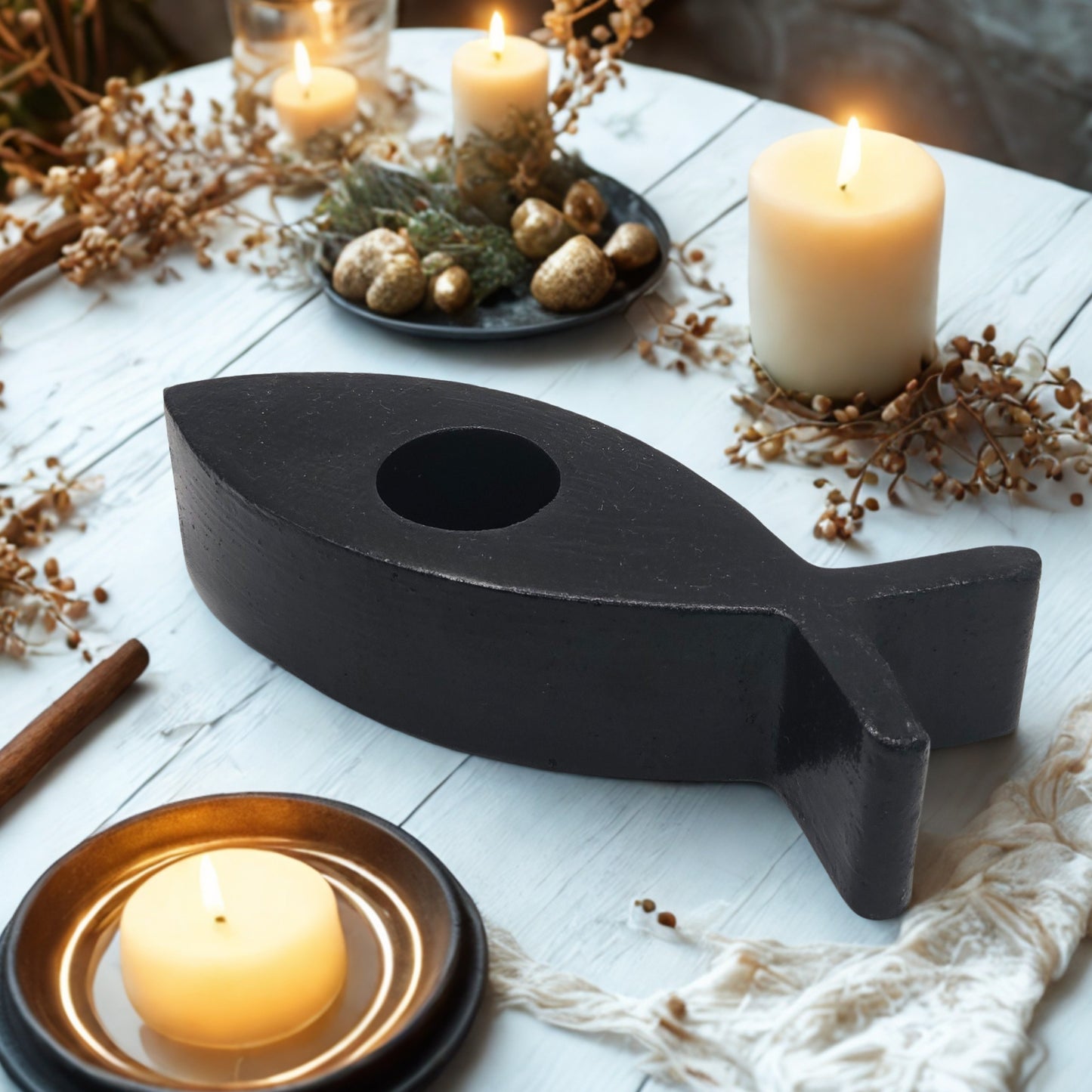 fish candle holder with lit candles on a white wooden surface.