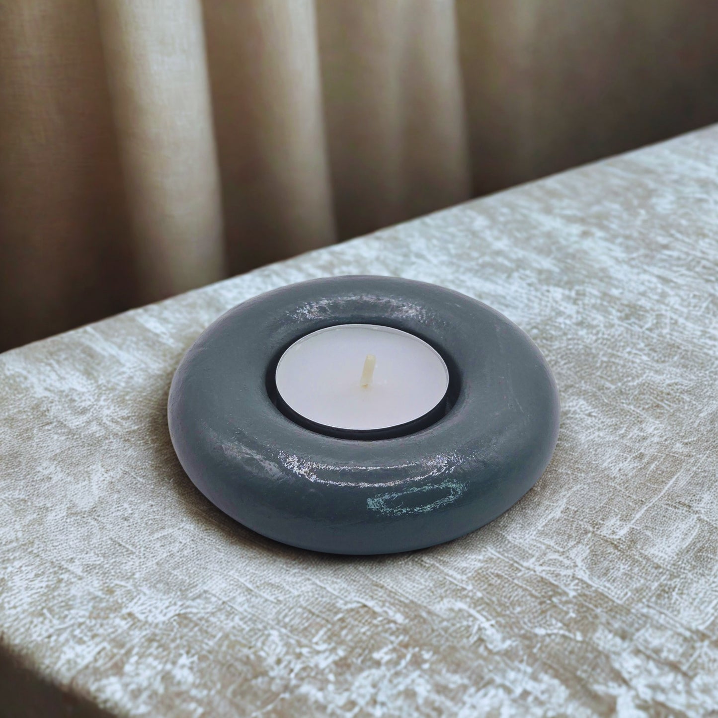 Gray object with a white candle on a textured surface
