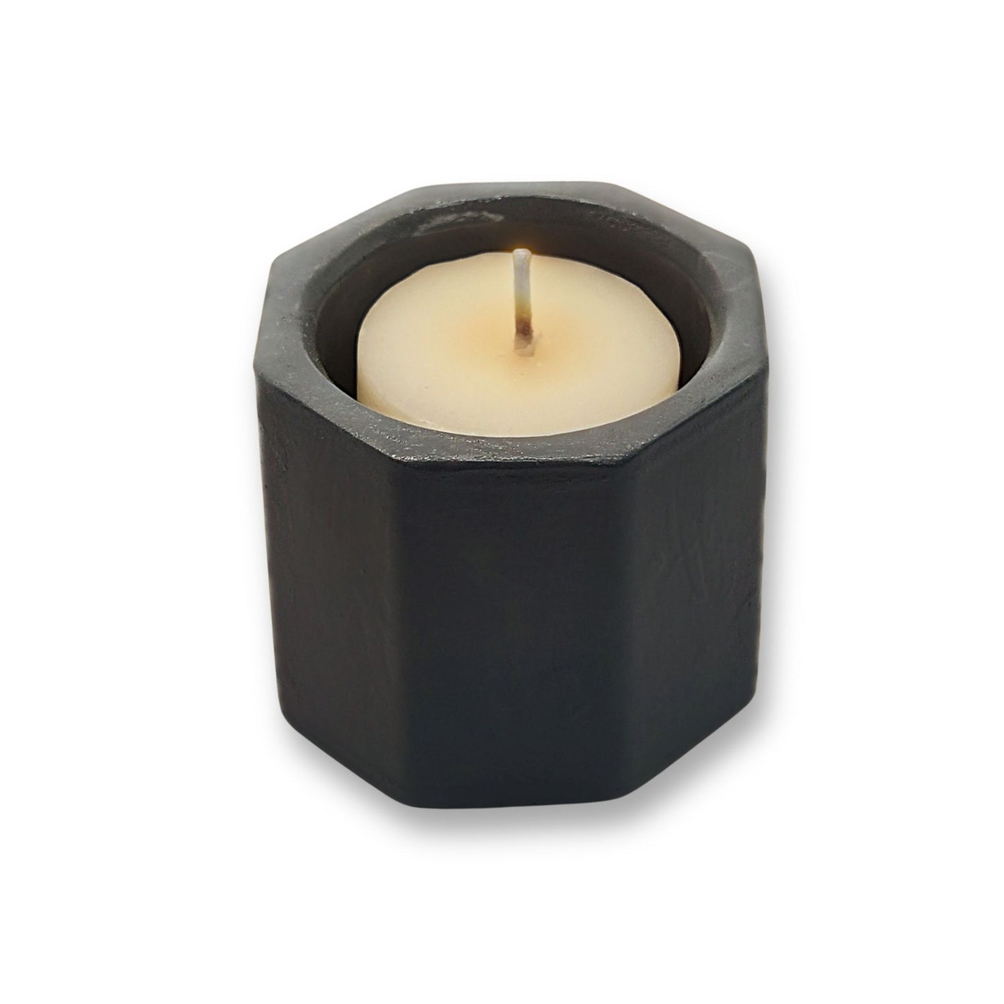 Hexagonal black candle holder with a white candle on a white background