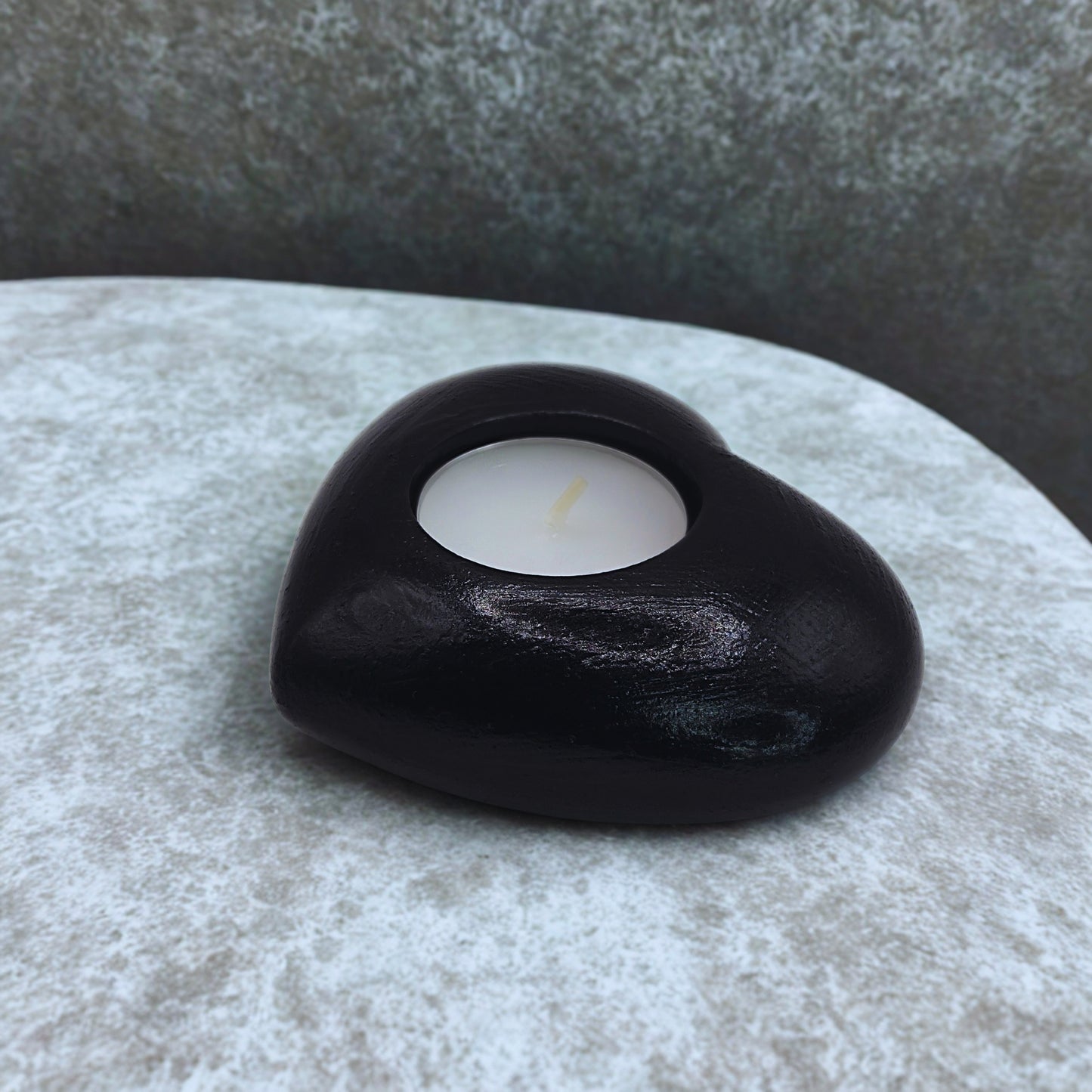 Black object with a white candle inside on a textured surface