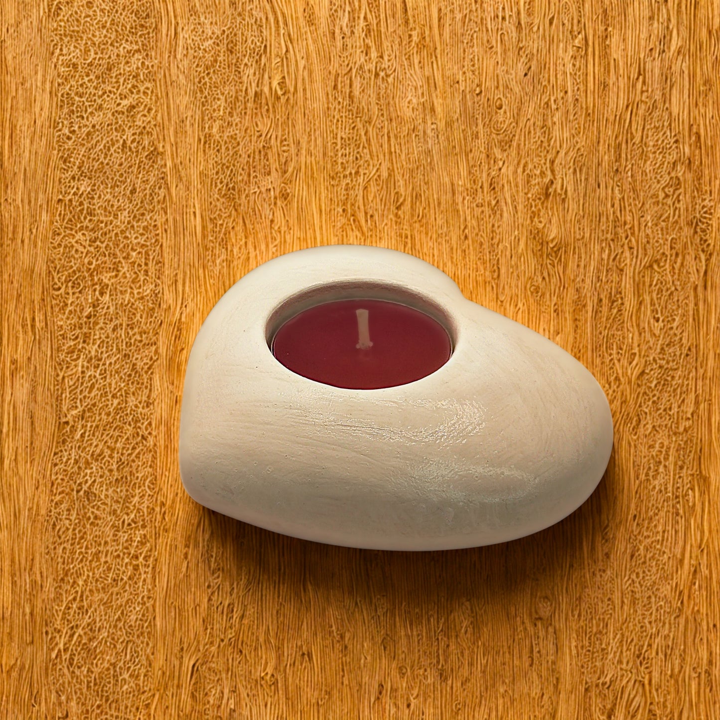 White Heart tealight holder with a red candle on a wooden surface