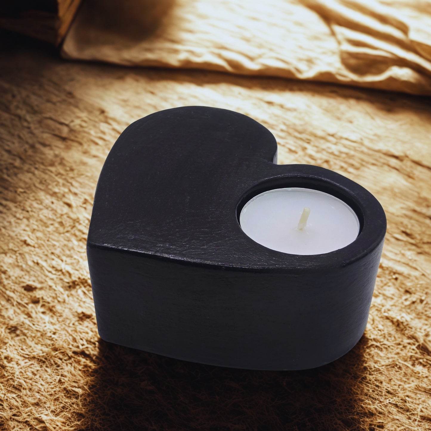 Black holder with a white candle on a textured surface