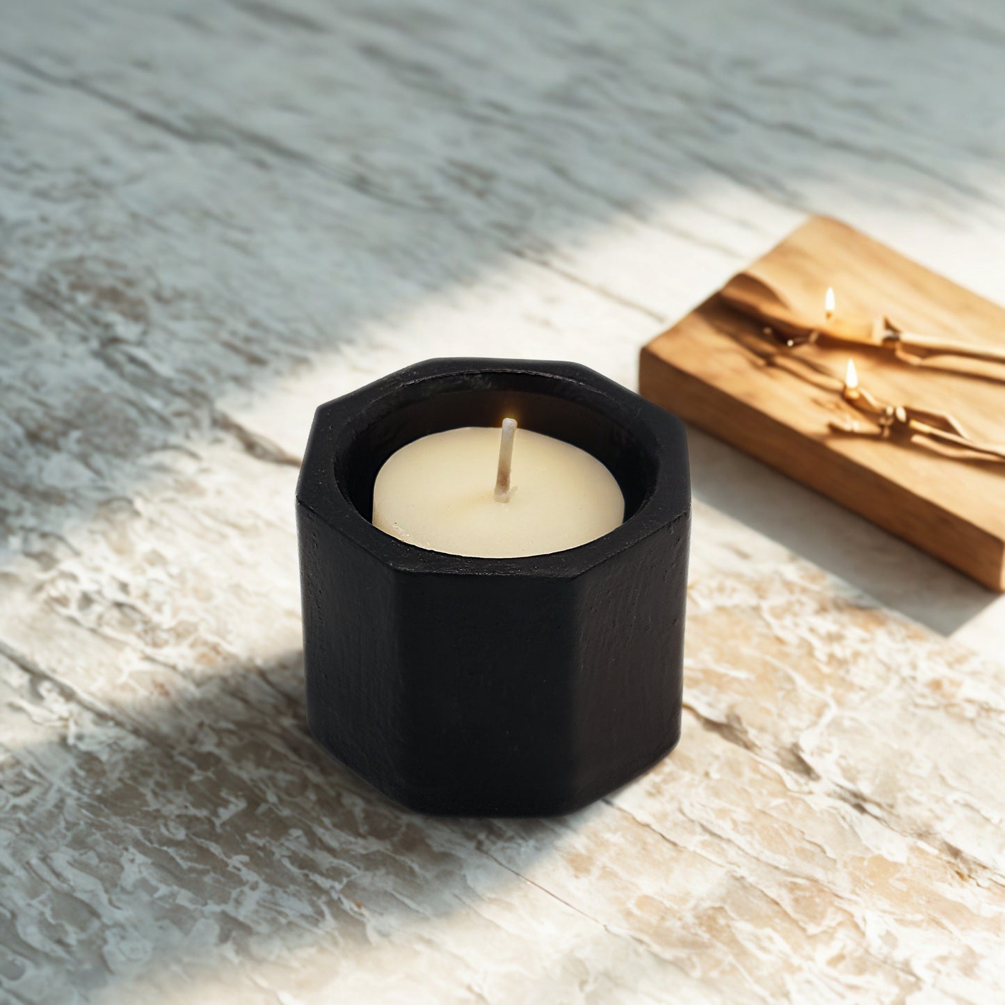 White candle in a black holder on a wooden surface