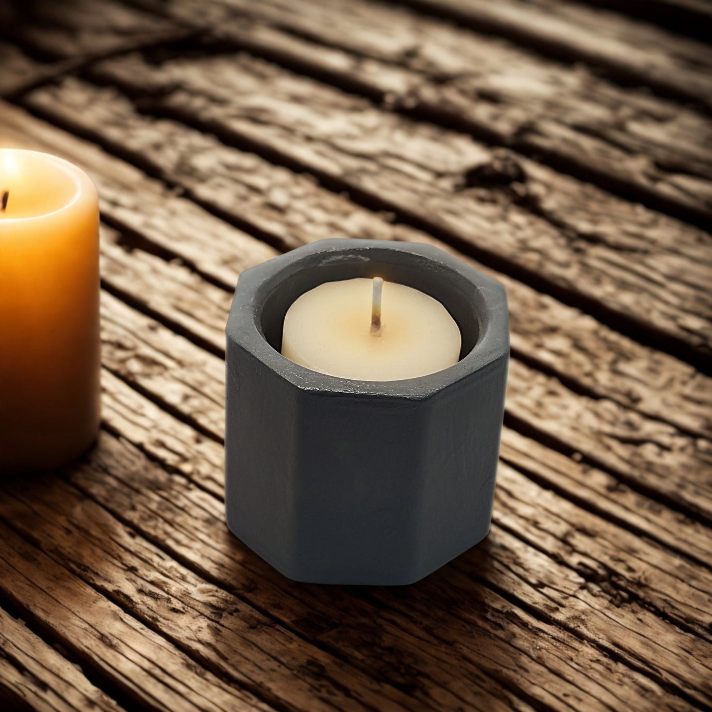 Hexagonal concrete candle holder with a white candle on a wooden surface