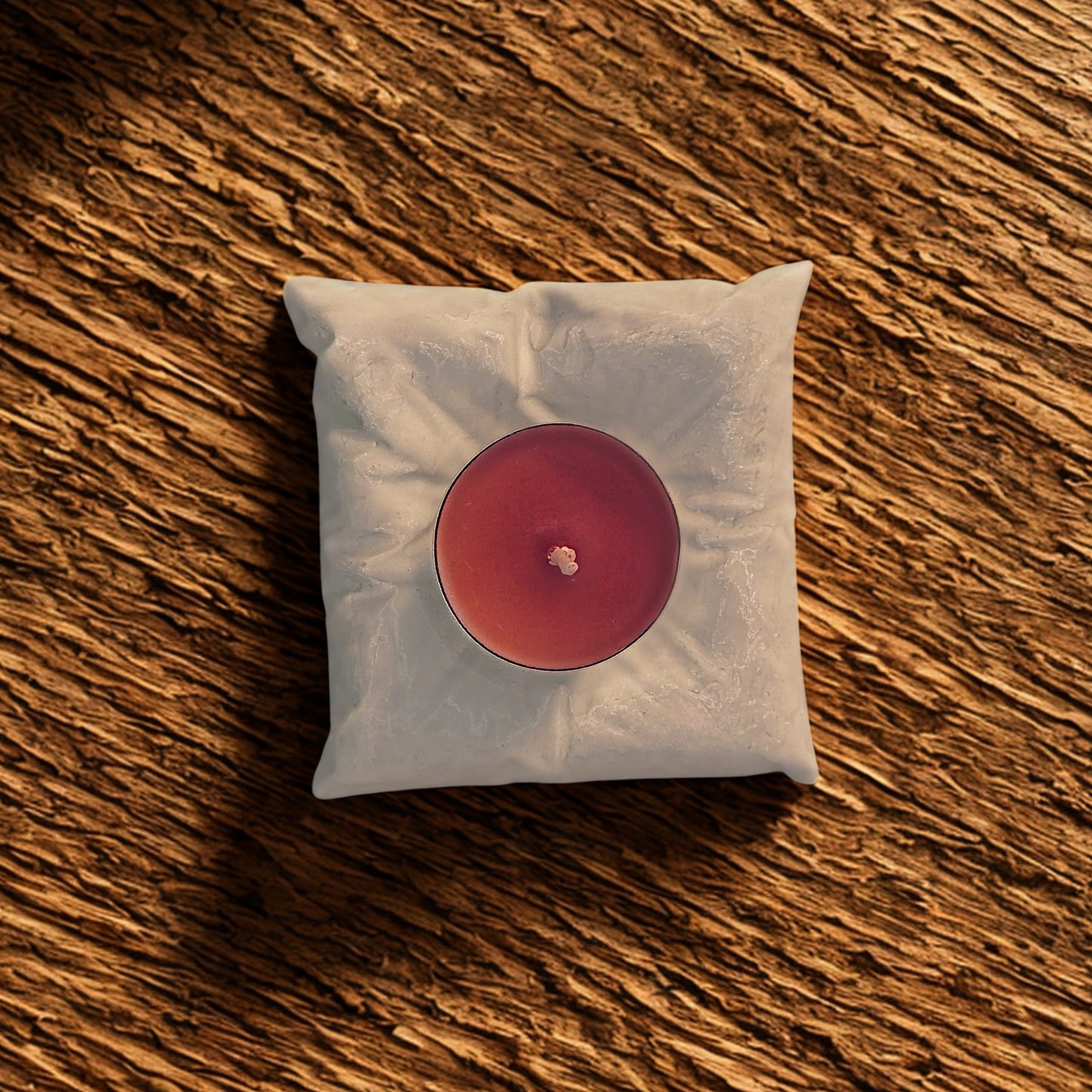 Red candle in a pillow tealight holder on a wooden surface