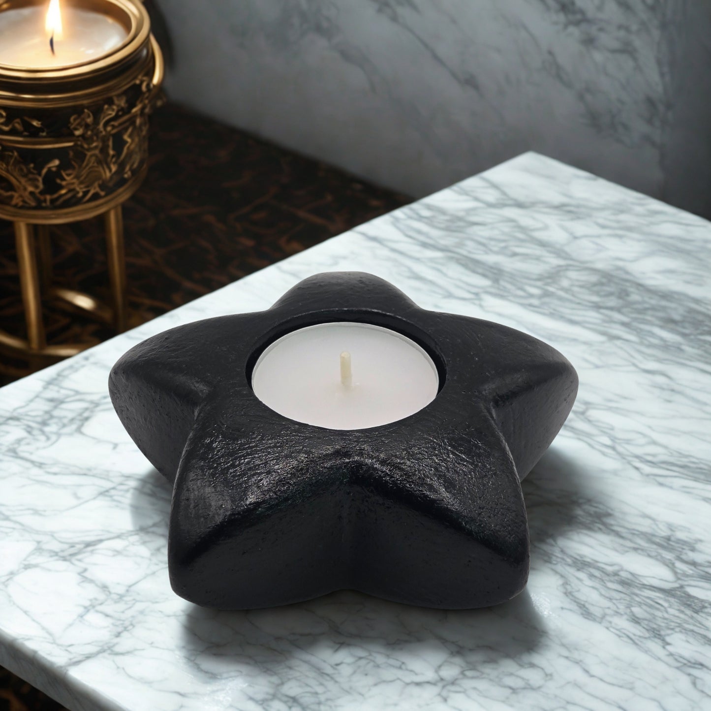 Black star-shaped object with a white candle on a marble surface.