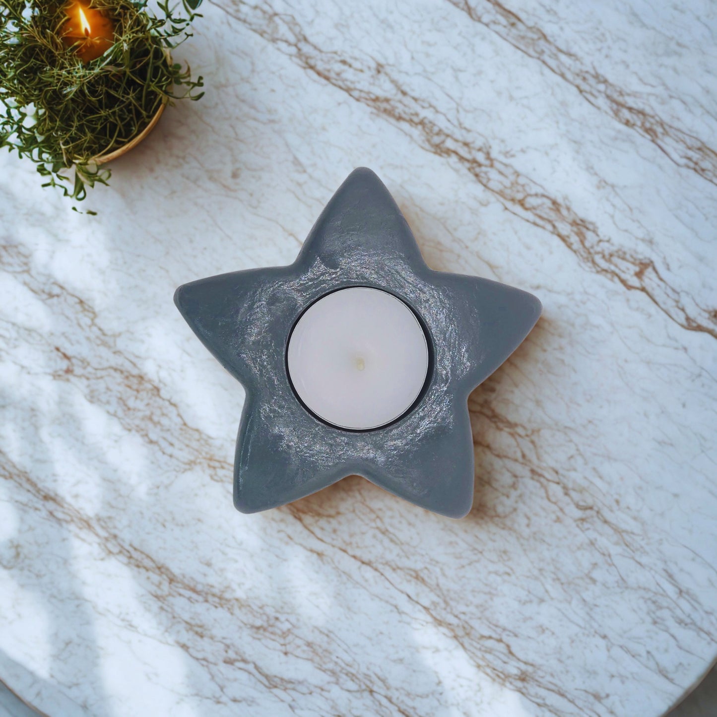 Star-shaped candle holder with a candle on a marble surface