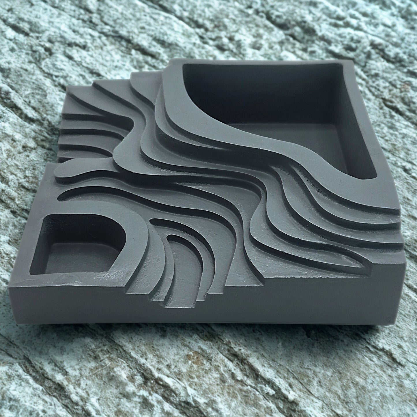 Gray step planter with wavy patterns on a stone surface