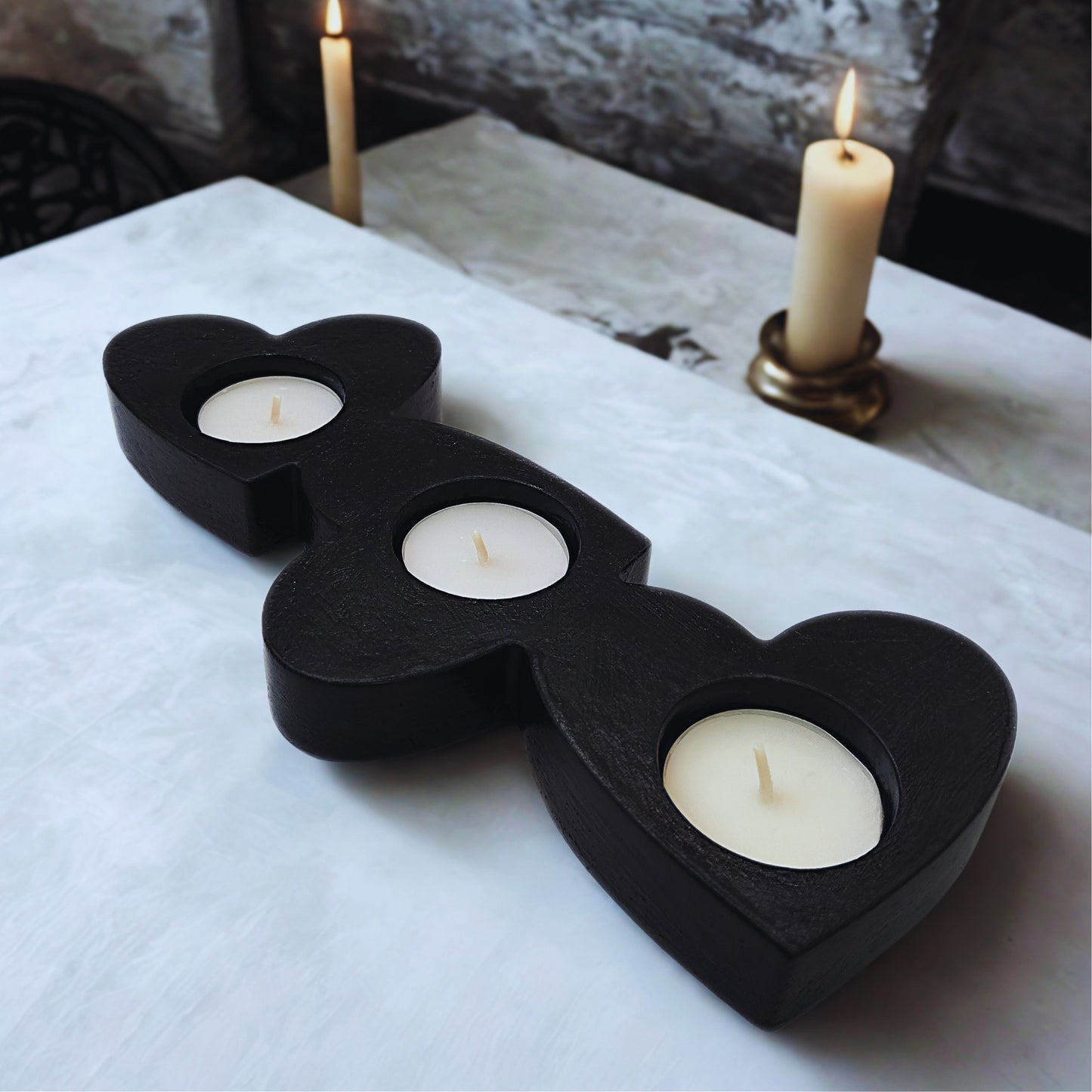 object with three white candles on a marble surface.