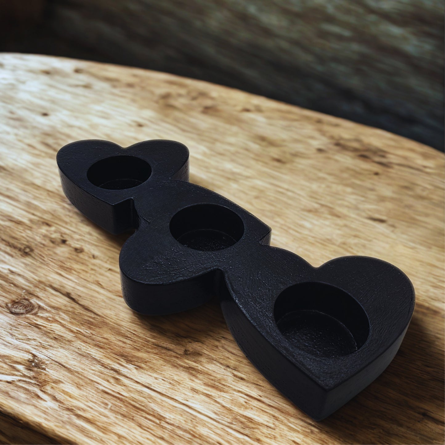 Black heart-shaped candle holder on a wooden surface