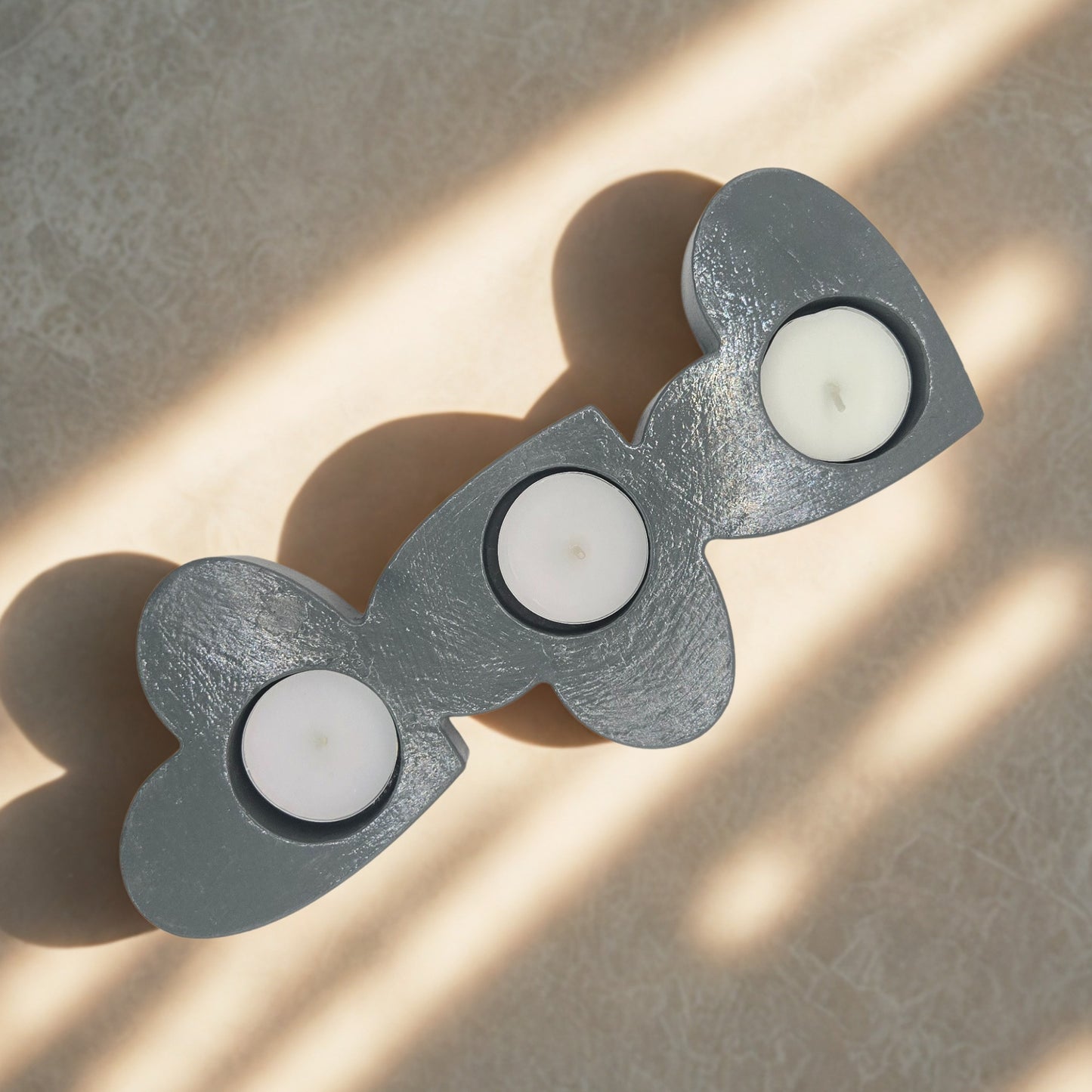Decorative candle holder with three candle holders on a textured surface