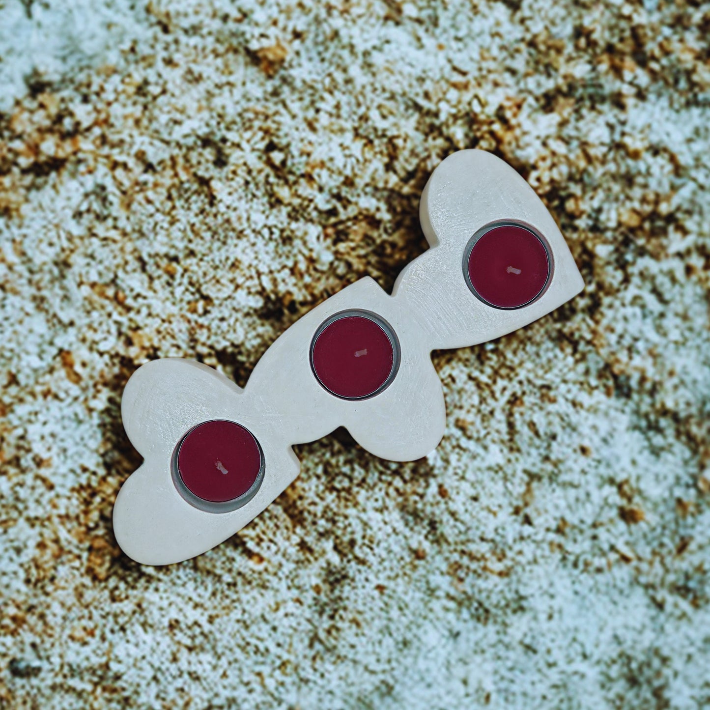 Triple Heart tealight holder with red centers on a textured surface
