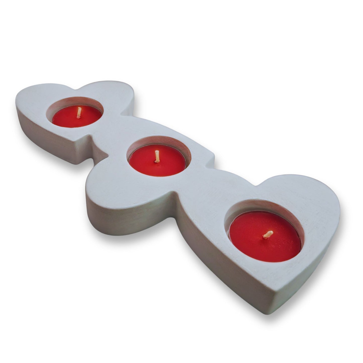Heart-shaped candle holder with three red candles on a white background