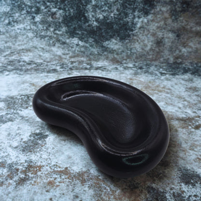 Black jellybean key bowl on a textured stone surface