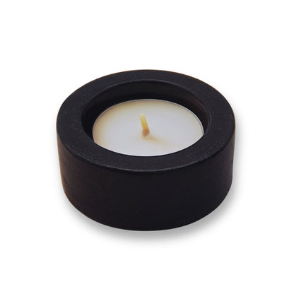 Black candle holder with a white candle on a white background