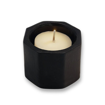 Hexagonal black candle holder with a white candle on a white background