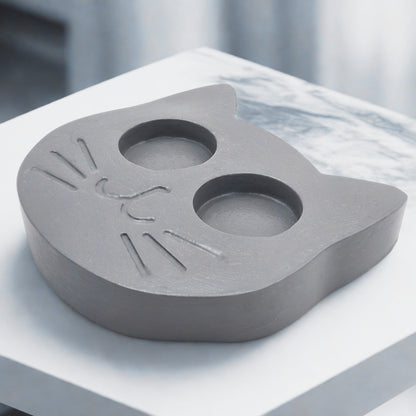 Gray shaped candle holder on a white surface with a blurred background