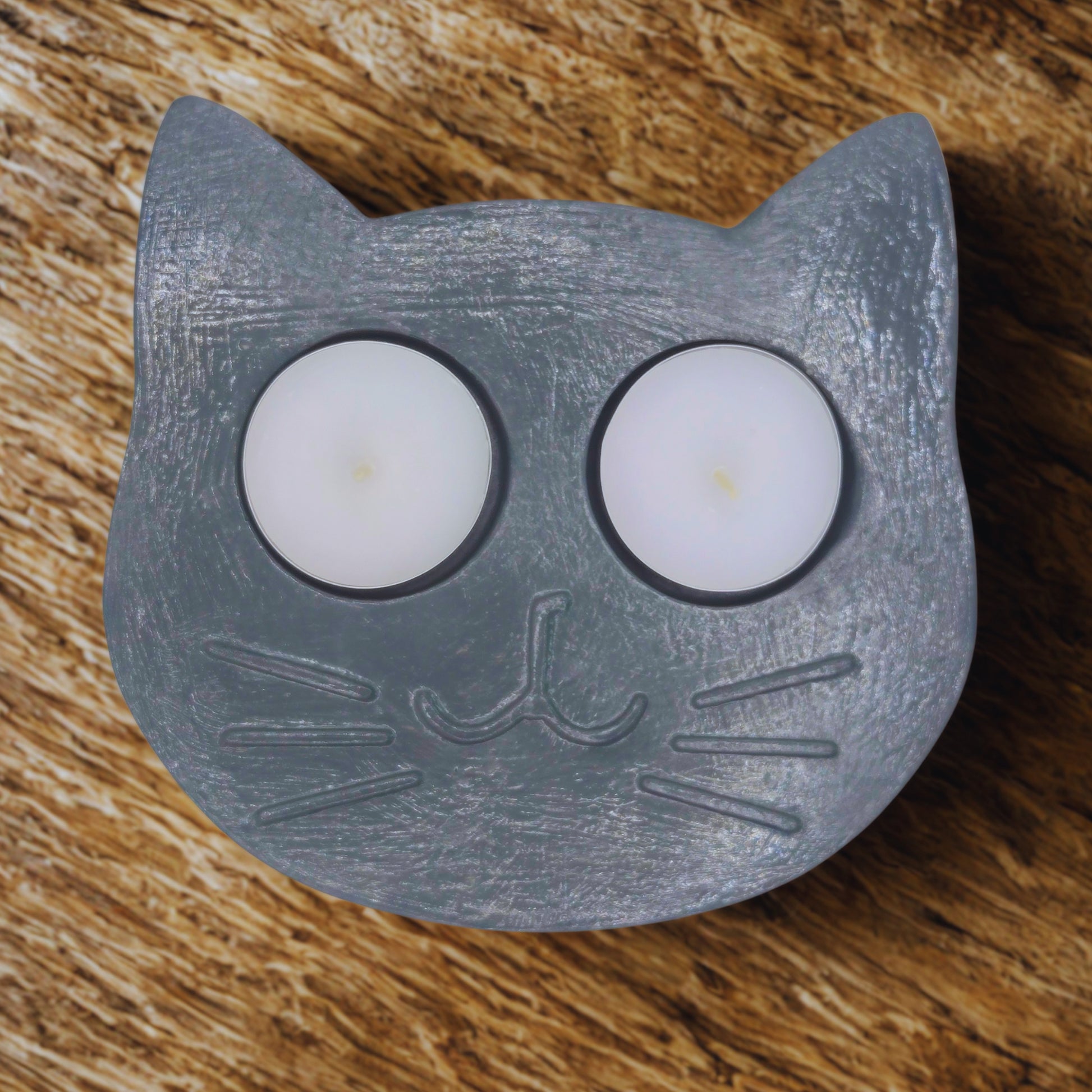 Grey shaped candle holder with two candles on a wooden surface