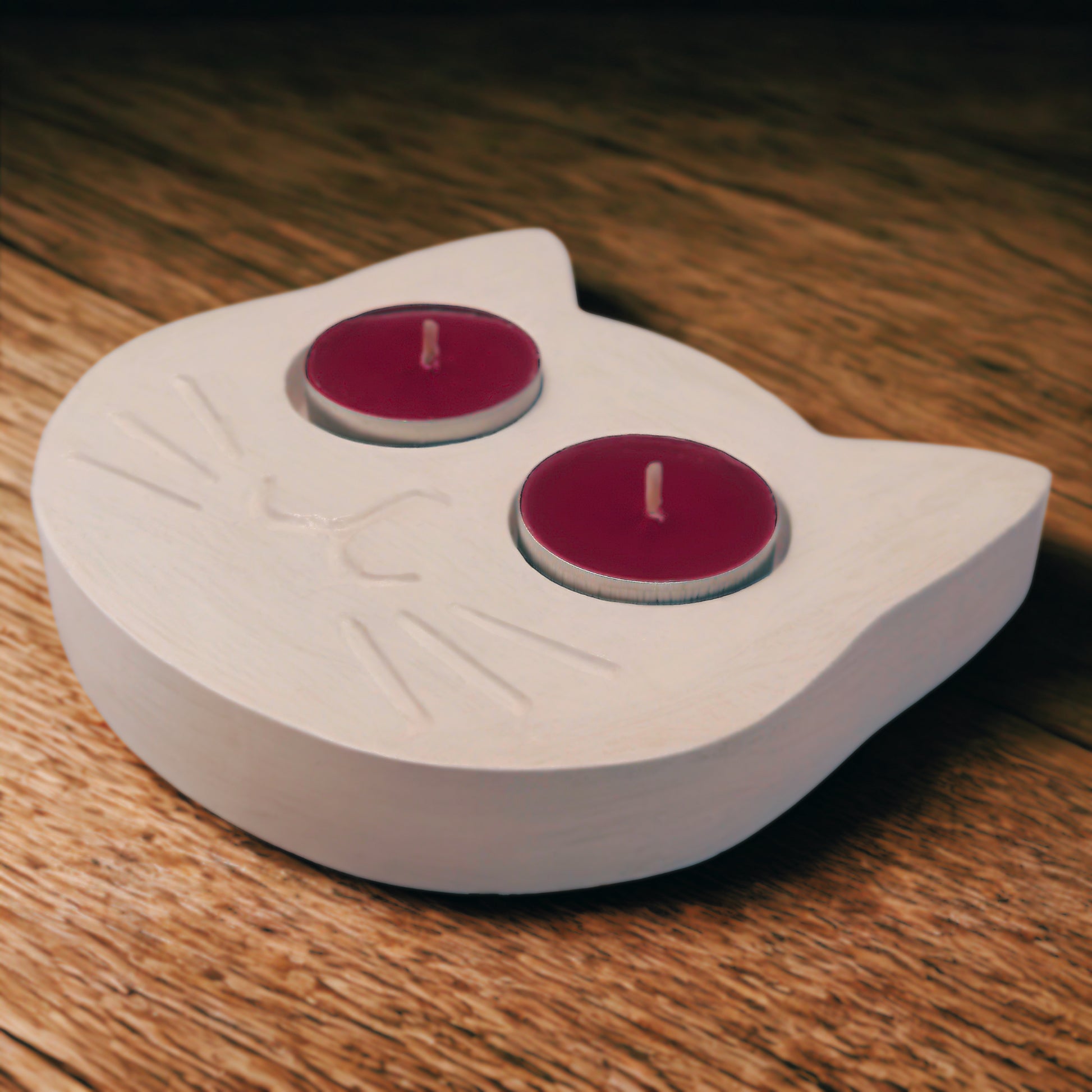 Cat-shaped candle holder with two red candles on a wooden surface
