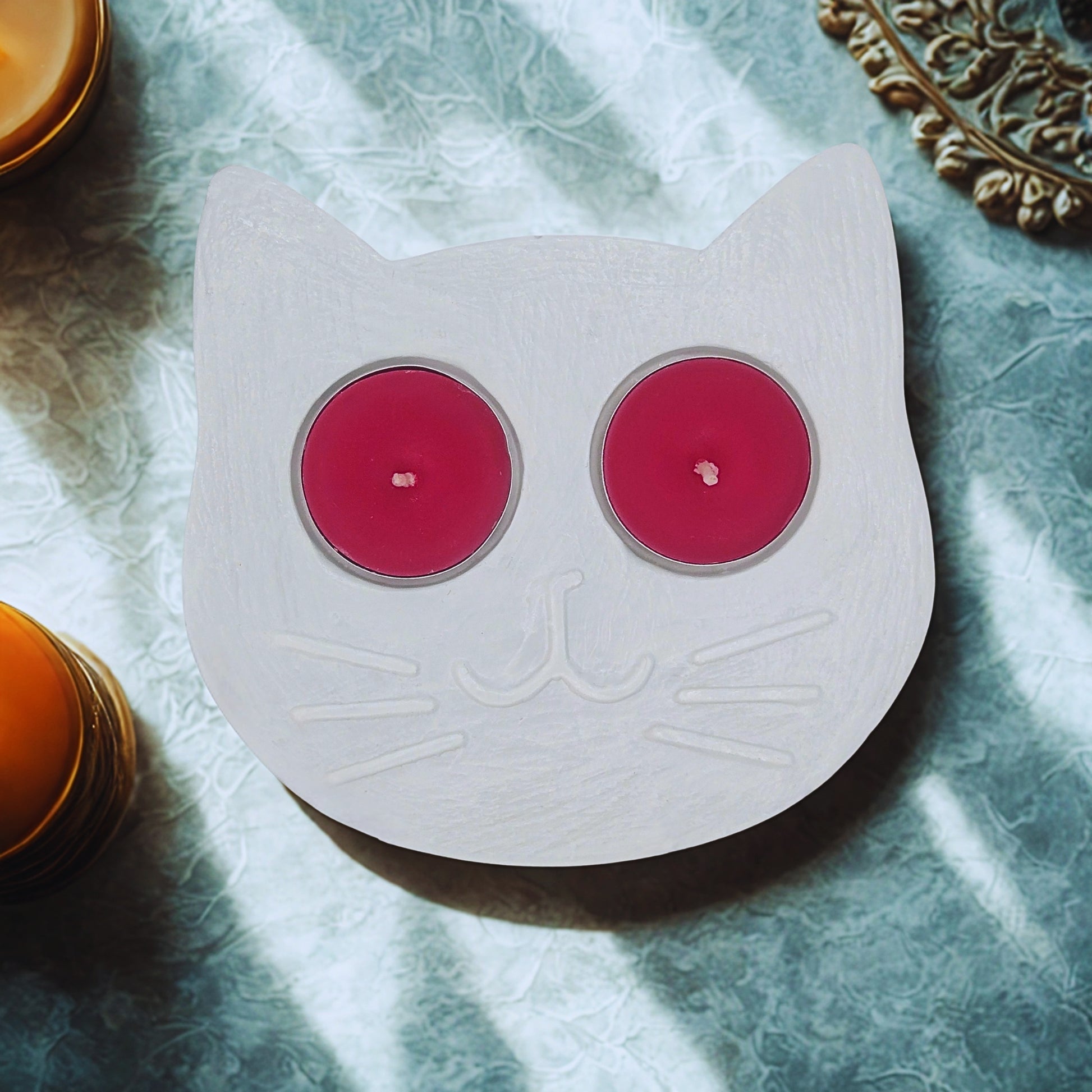 Cat-shaped candle holder with pink candles on a textured surface