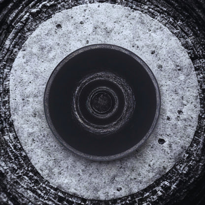 Close-up of a round candlestick holder with concentric circular patterns on a textured surface