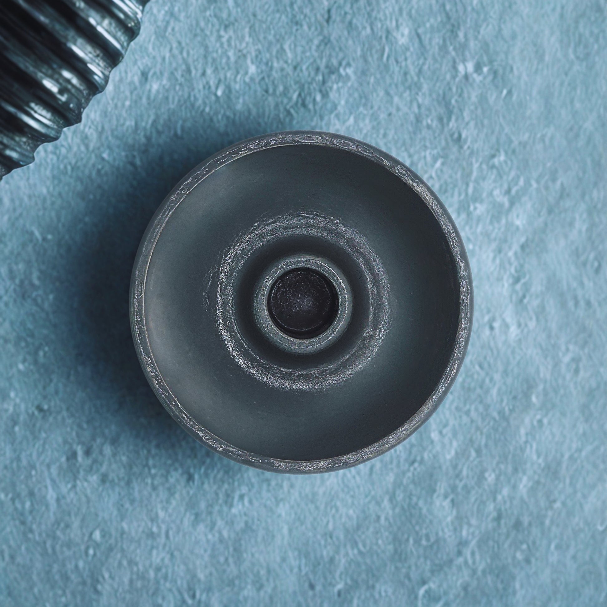Close-up of a round candlestick holder on a textured blue background