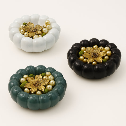 Three decorative items resembling pumpkins with floral and pearl designs on a white background