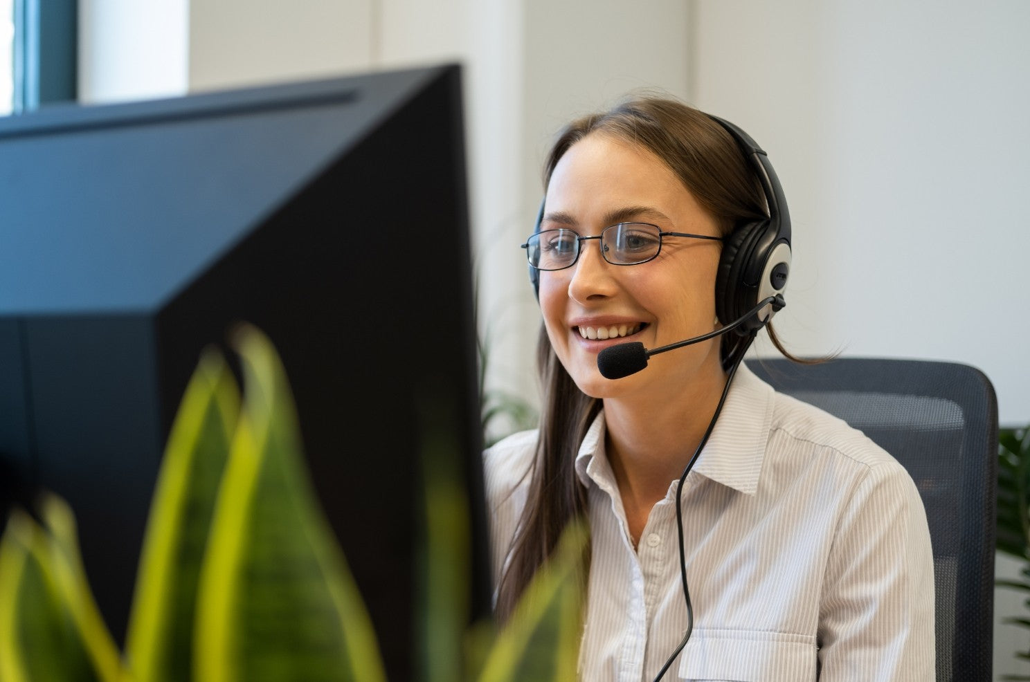 A woman sat at a desk with a headset on