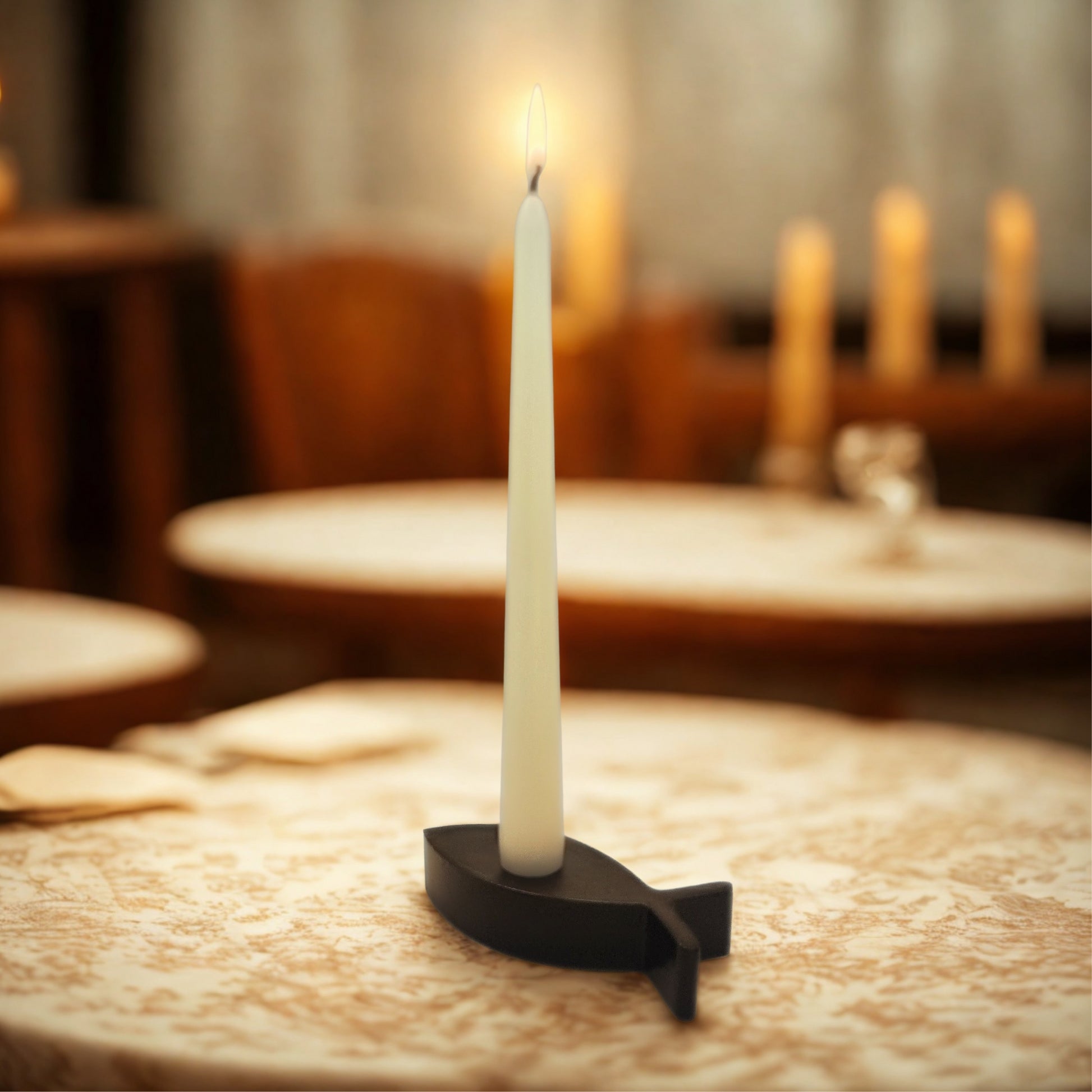 White candle on a black holder on a wooden table with blurred background