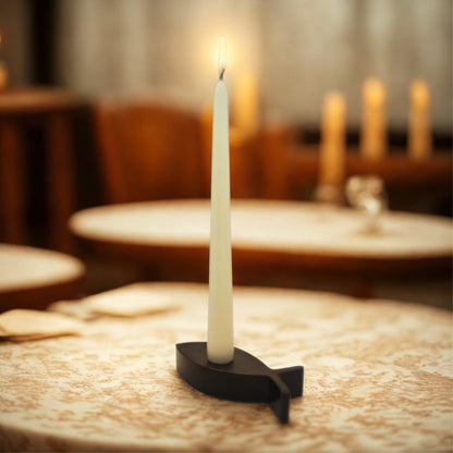 White candle on a black holder on a wooden table with blurred background