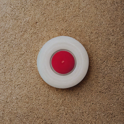Red candle in a white holder on a beige carpet