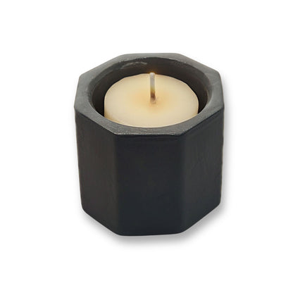 Hexagonal black candle holder with a white candle on a white background