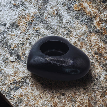 Black Heart tealight holder with a hole on a textured surface