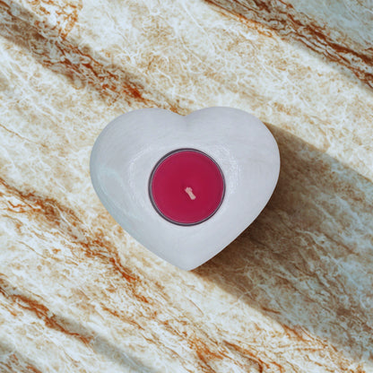 Heart tealight holder with a pink wick on a marble surface