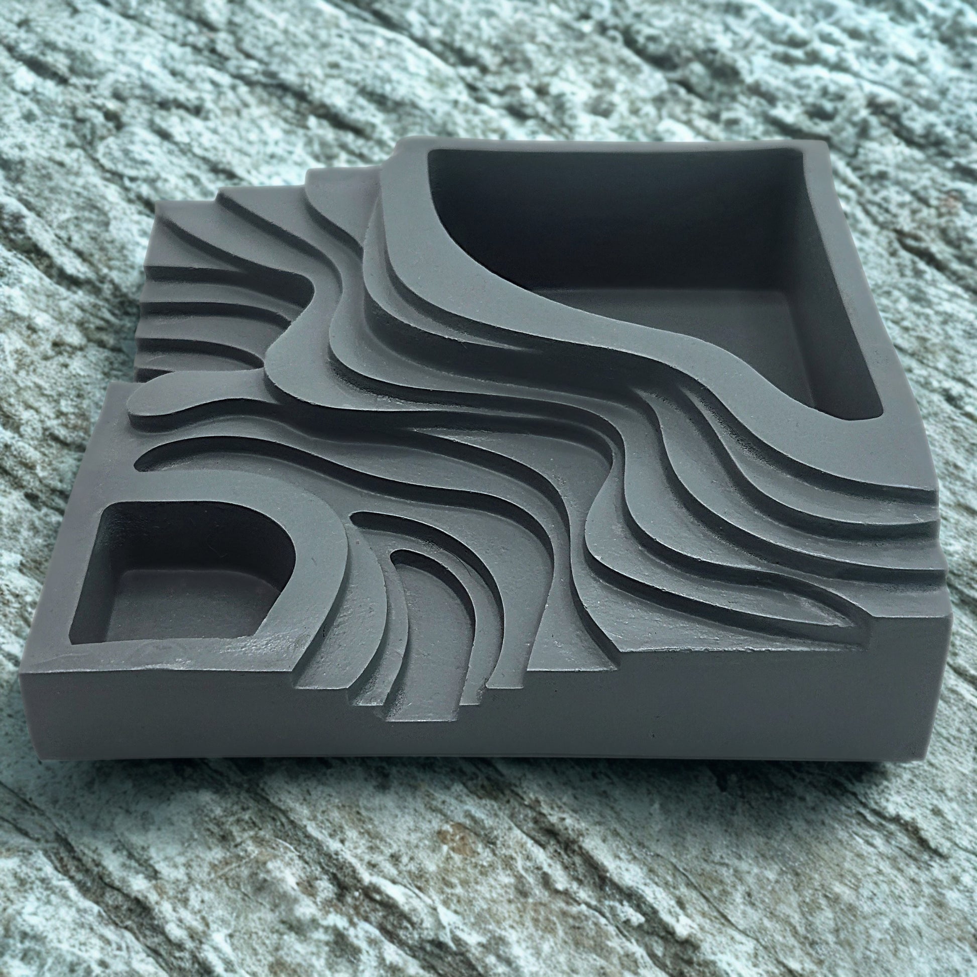Gray step planter with wavy patterns on a stone surface