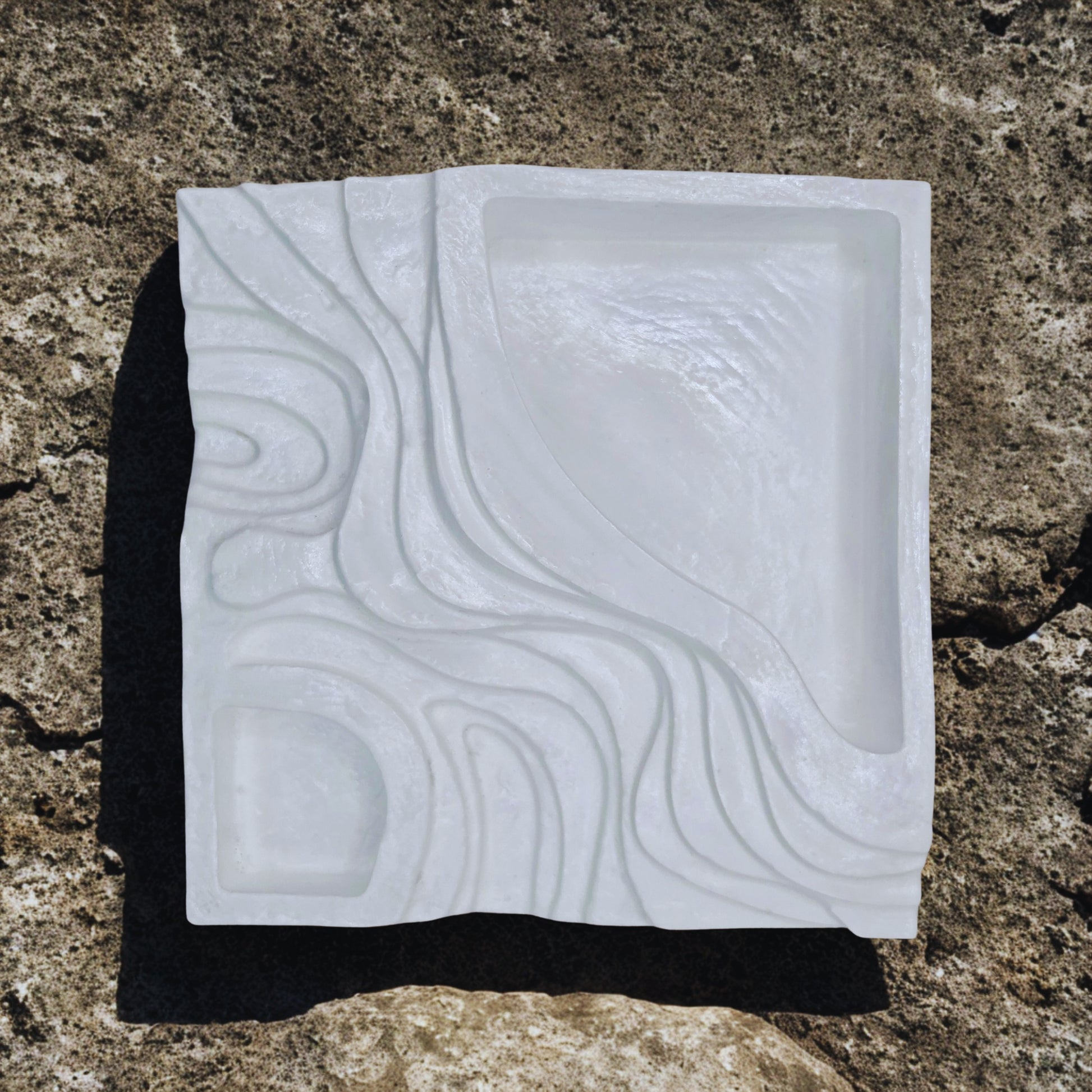 White object with embossed pattern on a textured brown surface